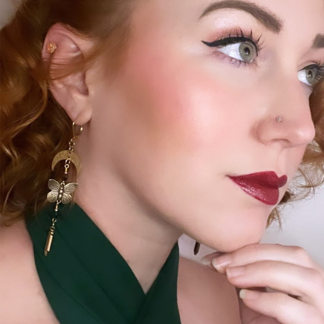 Pinup Model Miss Millie Michelle wears butterfly earrings gold moon charms with butterfly charms and bullet charms